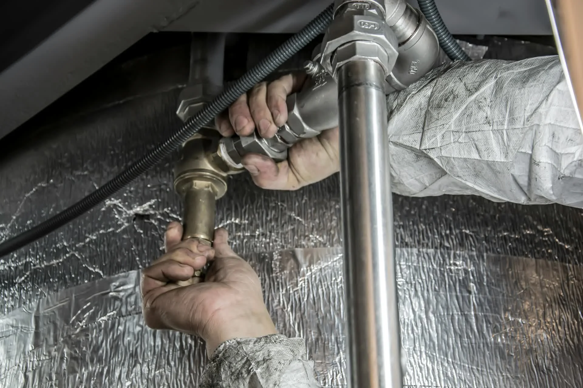 Technician connecting ductwork fittings in an insulated crawl space