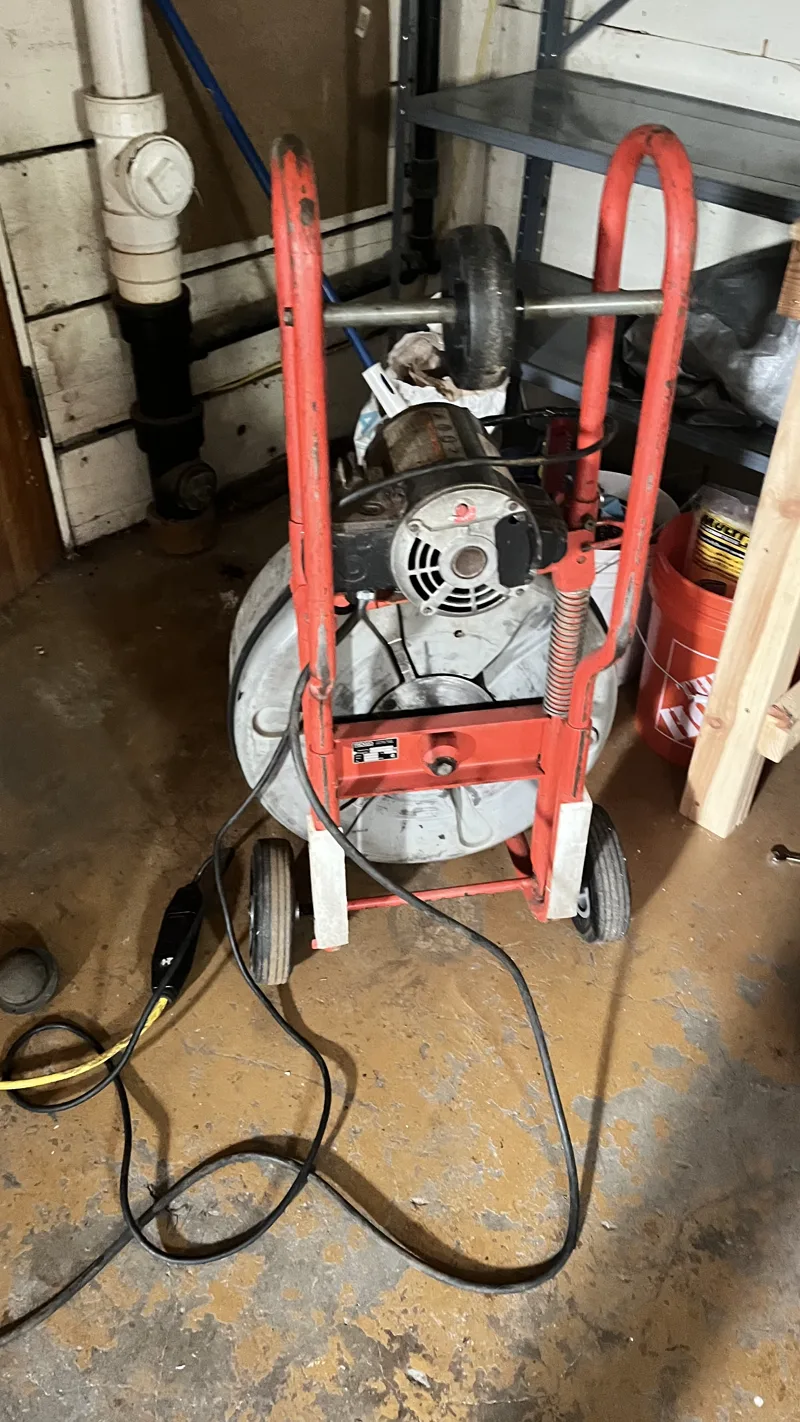 Drain cleaning machine set up beside an open sewer cleanout