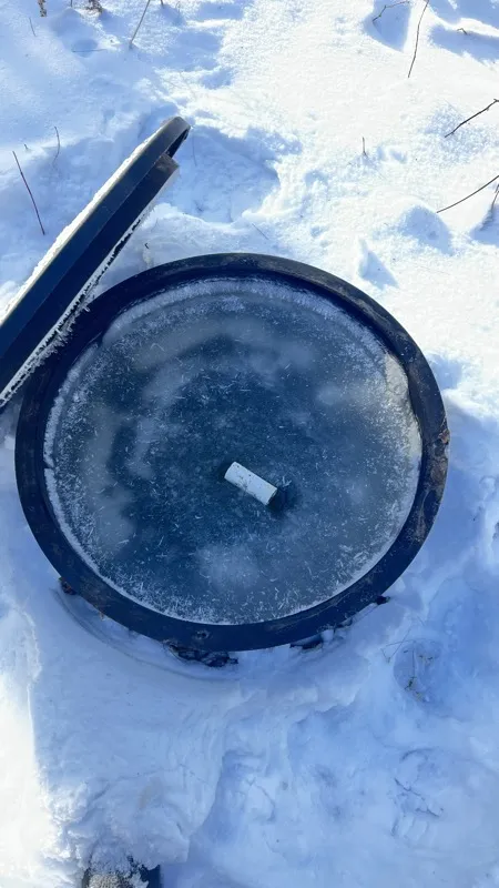 Snow-covered septic access lid opened for winter service in Northern Wisconsin